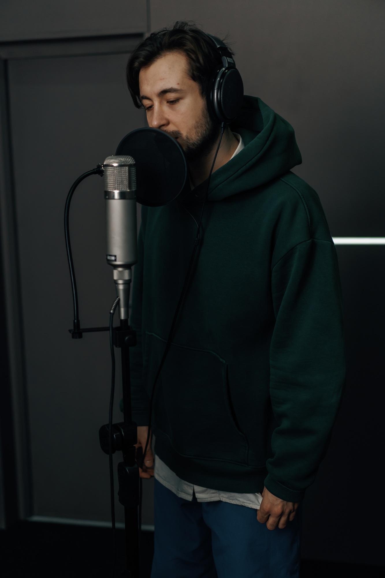 singer with headphones and microphone emotionally recording a song in a professional studio